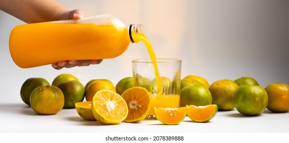 Closeup fat woman hand pouring fresh orange juice into glass. Glass with fresh orange juice and sliced orange in white background - Shutterstock ID 2078389888
