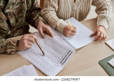 Closeup of father wearing military uniform helping daughter with homework, copy space - Powered by Shutterstock