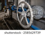 Close-up of a feedwater boiler valve in an industrial setting, featuring a large metal handwheel and pipeline system. Essential for controlling water flow and pressure regulation in boiler operations