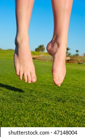 closeup of feet of jumping on green field woman