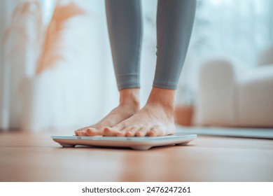 Closeup of feet, Young Asian woman standing on scales to measure her weight at home, Checking result of her slimming diet. Healthy living concept - Powered by Shutterstock