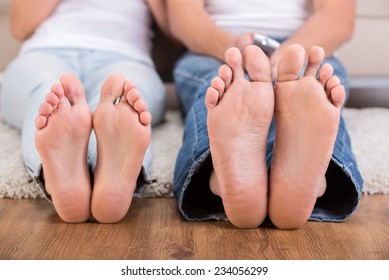 Close-up Feet Of Young Woman And Man Are Sitting On The Floor.