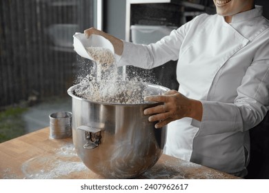 Closeup female baker chef mixing flour for sourdough in metal bowl - Powered by Shutterstock