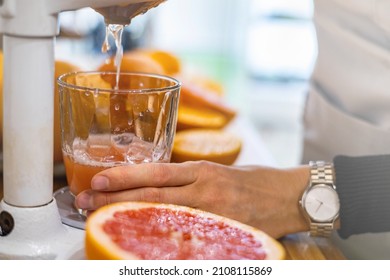 Closeup female bartender hands makes fresh detox grapefruit juice pulling handle professional citrus and pomegranate press. Woman kitchen staff cooking fruits refreshing vitamin drink in lever juicer - Shutterstock ID 2108115869