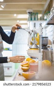 Closeup female bartender hands makes fresh detox grapefruit juice pulling handle professional citrus and pomegranate press. Woman kitchen staff cooking fruits refreshing vitamin drink in lever juicer - Shutterstock ID 2179856523