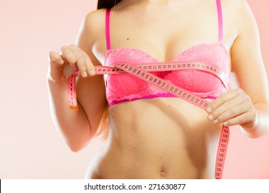 Closeup of female body. Fitness woman fit girl in pink lingerie with measure tape measuring her chest breasts