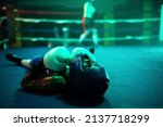 Close-up of female boxer knocked out in final round. Two young girls boxing on ring and one girl lying on floor after strong blows of her rival, loosing match. Extreme sport and womens boxing concept