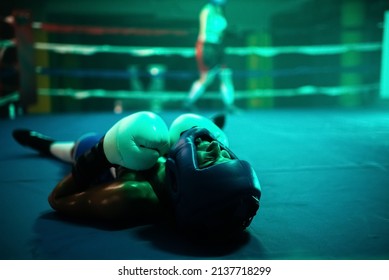 Close-up of female boxer knocked out in final round. Two young girls boxing on ring and one girl lying on floor after strong blows of her rival, loosing match. Extreme sport and womens boxing concept - Powered by Shutterstock