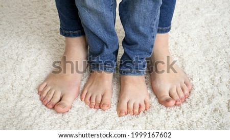 Closeup of female and child feet standing on soft carpet and moving toes