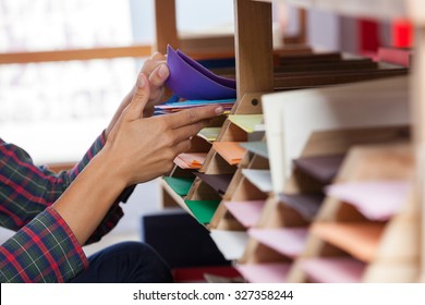 Closeup of female customer's hands selecting greeting card from shelf in shop