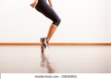 Closeup of a female dancer's tap shoes while she performs in a studio