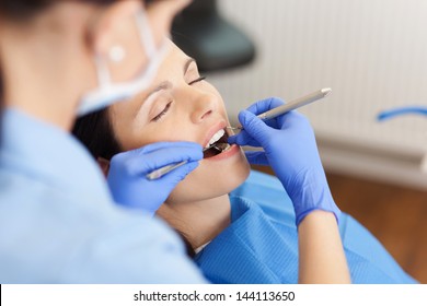 Closeup of female dentist examining mid adult patient's mouth in clinic - Powered by Shutterstock