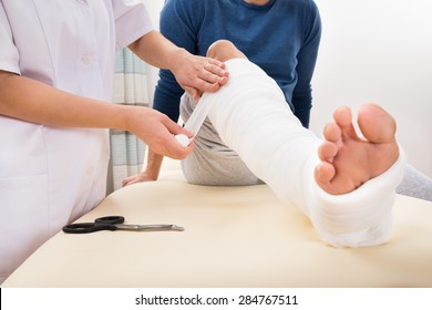 Close-up Of A Female Doctor Bandaging Patient's Leg