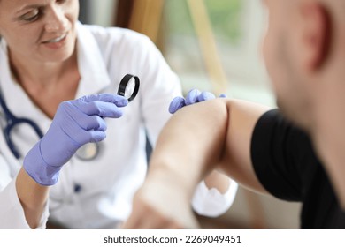 Close-up of female doctor examining male patient skin at consultation in medical clinic. Dermatologist checking patient's skin problems concept - Powered by Shutterstock