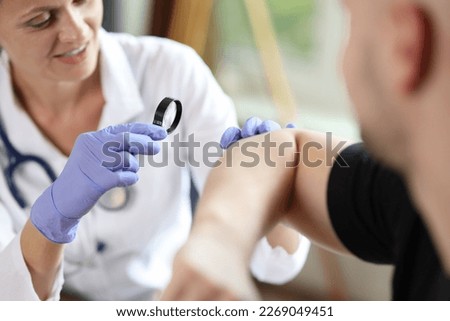 Close-up of female doctor examining male patient skin at consultation in medical clinic. Dermatologist checking patient's skin problems concept