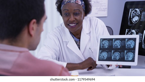 Closeup Of Female Doctor Explaining To Young Latino Patient Results From His Mri