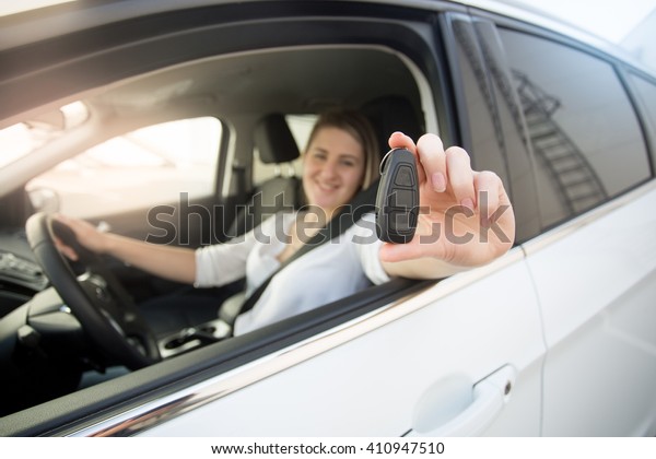 Closeup of female driver showing car keys through
open window