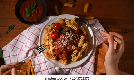 Closeup, Female Eats Tasty Italian Tomato Fusilli Pasta With Fork And Spoon In Vintage Dining Table.