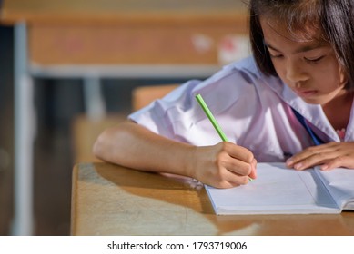 Close-up Of A Female Elementary School Asian Student Writing A Book With Her Right Hand.