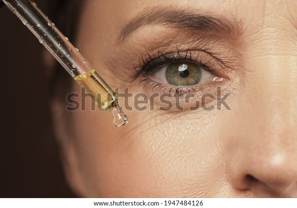 Closeup\
of female eye and dropper with rejuvenating\
serum