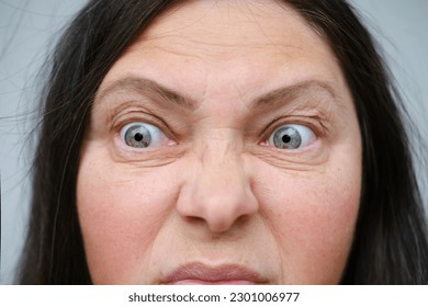 close-up female face makes negative grimaces aggression, mature woman 55 years old with foolish threatening facial expression, concept mental human health, optimism in adulthood, midlife crisis - Shutterstock ID 2301006977