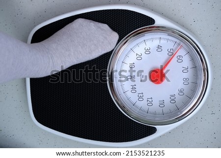 close-up of female feet on the floor in gray light cotton socks on floor mechanical scales in vintage style, concept of women's health, weight control, diet and nutrition, lose weight