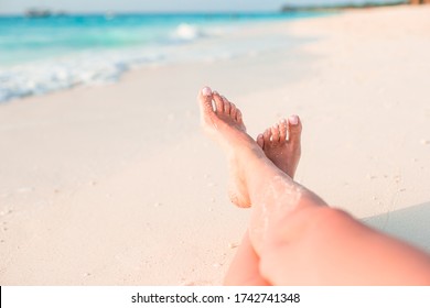 Closeup female feet on white sand beach