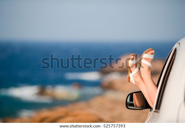 Closeup of female feet showing from car window
background sea