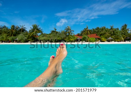 Close-up of female foot in the blue water on the tropical beach. Vacation holidays.