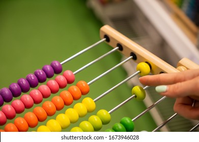 Closeup female hand calculating with balls on wooden rainbow abacus for number calculation. The concept of learning arithmetic for preschoolers.