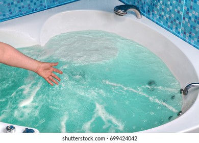 Close-up Of A Female Hand Checks The Water Temperature In The Whirlpool Hot Tub.