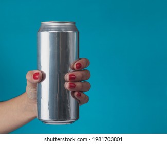 Close-up Of Female Hand Holding Aluminum Can Of Beverage, Beer, Soda Or Soft Drink. On Light Blue Background. Copy Space For Text.