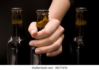Close-up Of A Female Hand Holding A Bottle Beer Isolated On Black