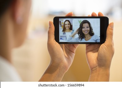 Closeup Of A Female Hand Holding A Cell Phone During A Skype Video Call With Her Friend 