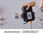 Closeup of female hand holding pro DSLR camera and taking product pictures in minimal studio set copy space