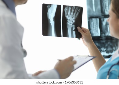 Close-up of female hand holding skiagram. Doctor talking about diagnosis of injured patient. Surgeon writing information. Healthcare and traumatology concept - Powered by Shutterstock