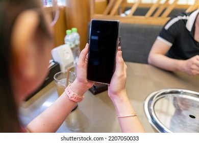 Closeup Of A Female Hand Holding A Smart Phone, Showing Smart Phone With Blank Screen , Black Screen For Mobile App Advertising, Display Mock Up Image