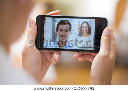 Closeup of a female hand holding a smart phone during a skype video call with her friend 