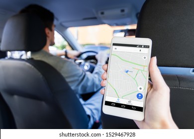Closeup female hand is holding smartphone with online map on screen, shows way to home. Woman is riding on back seat of automobile car. Taxi booking application, mobile GPS navigator concept.