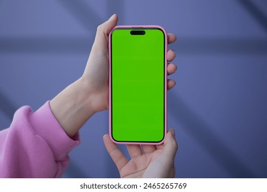 Closeup female hand holding smartphone green layout screen geometric blue background. Use technology. Apps, online shopping, artificial intelligence, challenge, mockup or template. Website or Internet - Powered by Shutterstock