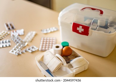 Closeup female hand neatly placing medicament at domestic first aid kit top view. Storage organization in transparent plastic box drug, pill, syringe, bandage. Fast health help safety emergency supply - Shutterstock ID 2044597436