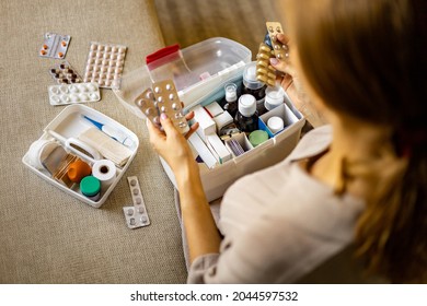 Closeup female hand neatly placing medicament at domestic first aid kit top view. Storage organization in transparent plastic box drug, pill, syringe, bandage. Fast health help safety emergency supply - Shutterstock ID 2044597532