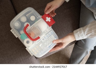Closeup female hand neatly placing medicament at domestic first aid kit top view. Storage organization in transparent plastic box drug, pill, syringe, bandage. Fast health help safety emergency supply - Shutterstock ID 2144927017