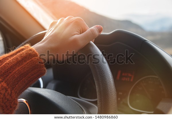Close-up of a\
female hand in an orange sweater driving a car outside the city.\
Slow motion Woman driving a\
car