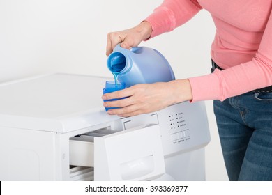 Close-up Of Female Hand Pouring Detergent In The Blue Bottle Cap