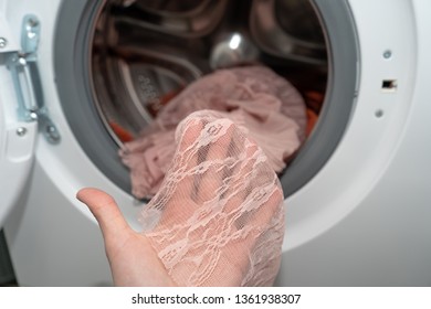 Close-up. Female Hand Showing Lace Of A Pink Dress Just Washed In An Automatic Washing Machine, Delicate Wash Mode 