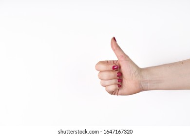 Closeup of female hand showing thumbs up sign against white background. - Shutterstock ID 1647167320