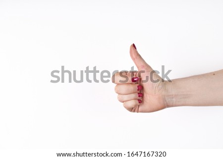 Closeup of female hand showing thumbs up sign against white background.