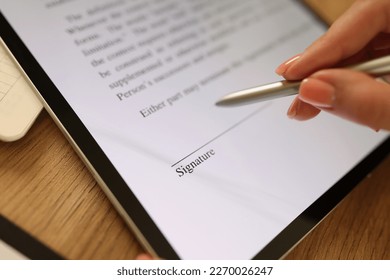 Close-up of female hand signing e-document with stylus on tablet. Electronic signature and modern technologies concept