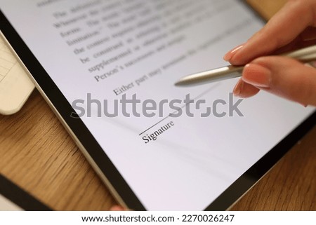 Close-up of female hand signing e-document with stylus on tablet. Electronic signature and modern technologies concept Foto stock © 